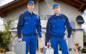 Two pest control technicians in uniform hold cases filled with pest control equipment